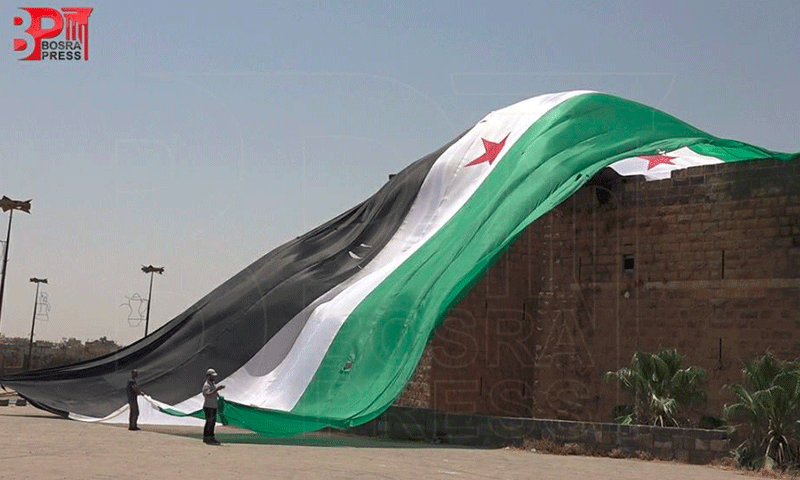 رفع أكبر علم للثورة السورية في الجنوب على قلعة بصرى الأثرية